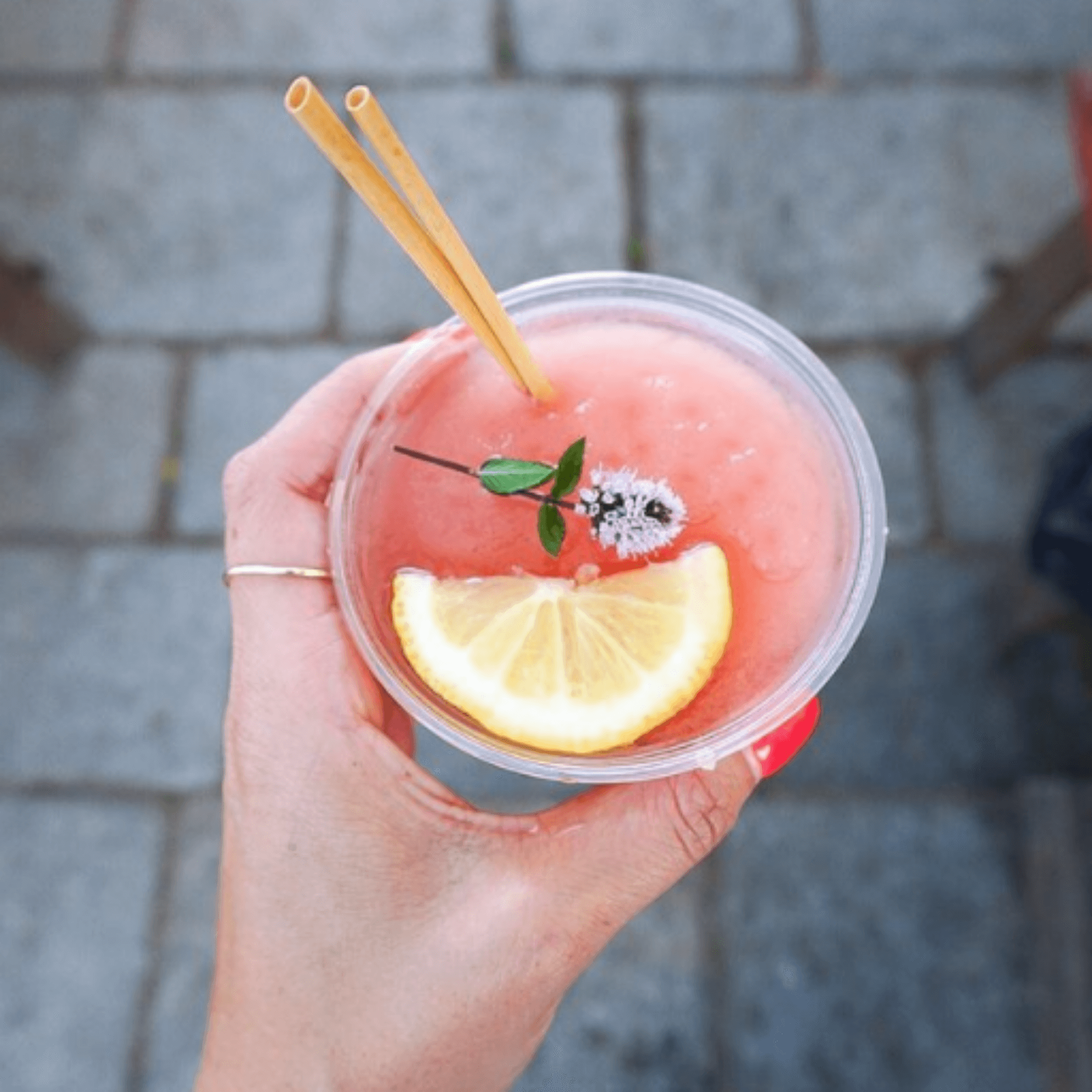 hand holding iced lemonade with cocktail wheat straw