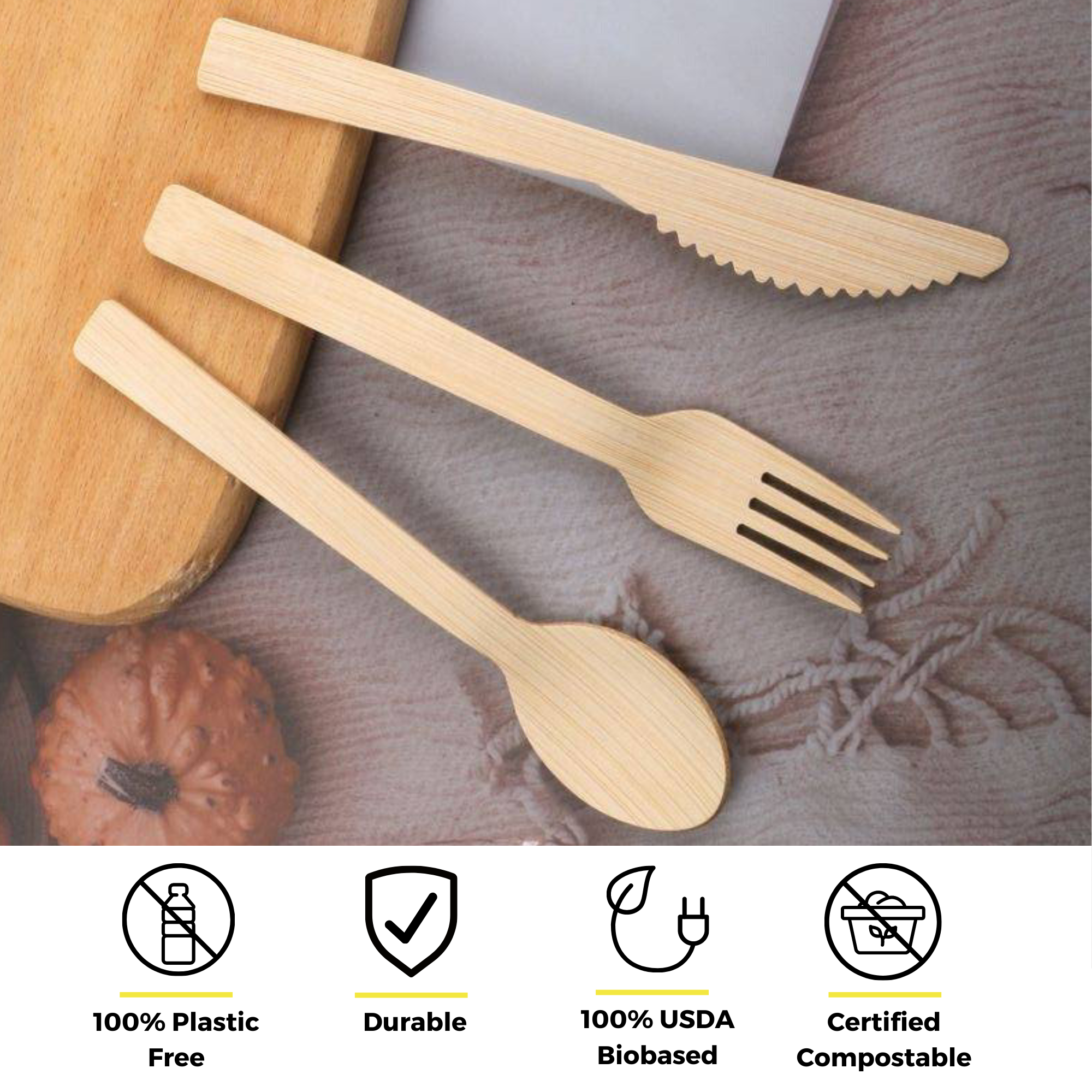 Sustainable bamboo cutlery by Holy City Straw Co., consisting of a spoon, fork, and knife, laid out on a fabric surface with a rolling pin partially visible. The image is accentuated with icons indicating the product's eco-friendly attributes: 100% Plastic Free, Durable, 100% USDA Biobased, and Certified Compostable.