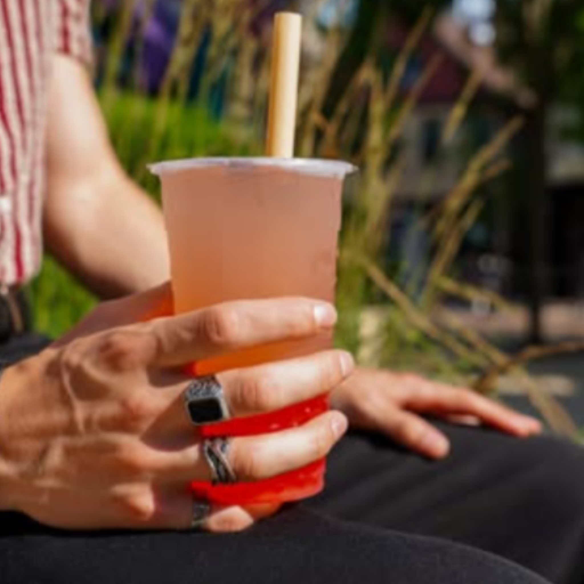 Hand holding an iced bubble tea with a bamboo fiber boba straw, captured outdoors in natural light, showcasing plant-based, durable straw alternative.
