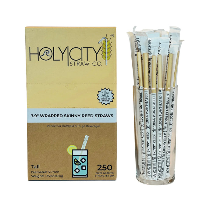 Holy City Straw Co. box of 250 7.9-inch wrapped skinny reed straws displayed next to a glass filled with unwrapped straws, suitable for hot, cold, and to-go beverages.