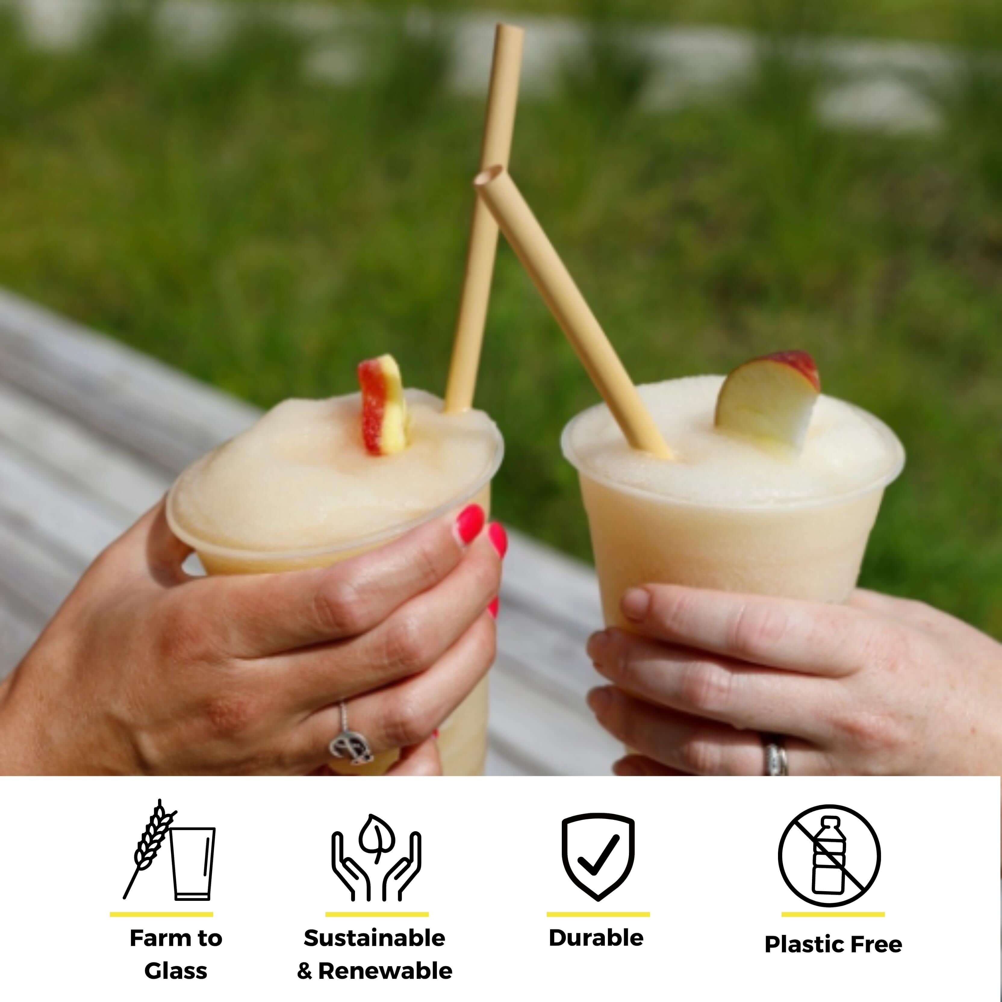 Two people are holding frozen drinks in clear cups garnished with apple slices. Both drinks feature biodegradable bamboo straws. One person has pink nail polish, and the other is wearing a silver ring. The image emphasizes sustainability, with icons beneath representing 