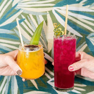 two hand cheersing island and fruit punch cocktail with wheat straw
